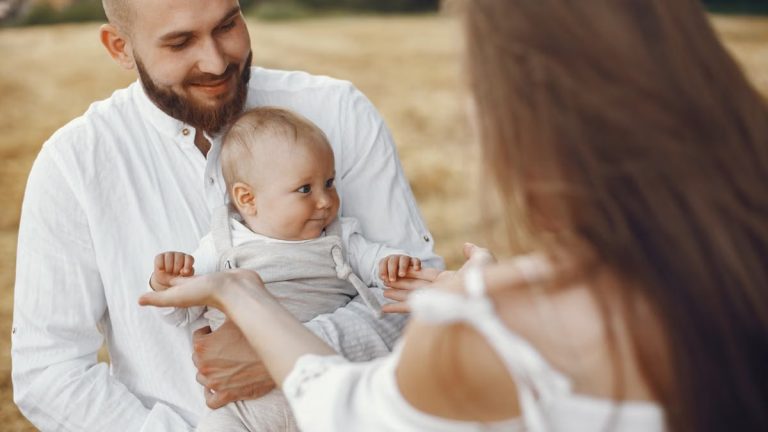 A joyful family moment captured outdoors with parents holding their baby.